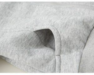 Detailed close-up of grey knit fabric, pocket seams, and ribbed cuff on boys' hoodie