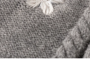 Detailed macro view of dark grey chunky knit fabric with white floral embroidery