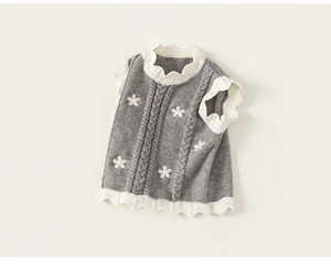 Detailed view of dark grey knitted vest with white flower embroidery and wavy ruffle hem