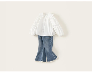 Detail of white ruffle trim long sleeve shirt and blue denim flare jeans with lace hem