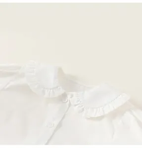 Close-up of white girls' blouse featuring a ruffled Peter Pan collar and neat buttons
