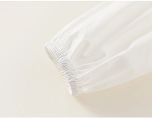 Close-up of white cotton shirt sleeve with elastic smocked cuffs and fine pleat details