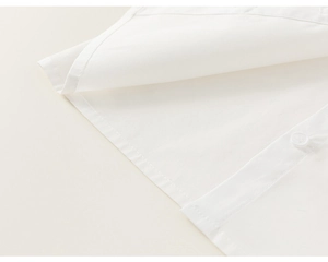 Detailed close-up of white cotton shirt hem with fine stitching and matching button