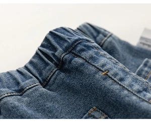 Detail of toddler girl jeans with elastic waistband and yellow contrast stitching