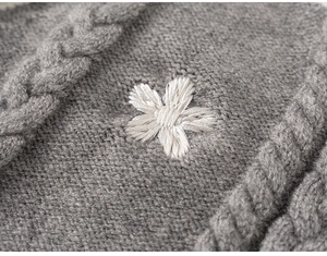 Detail of grey cable knit fabric featuring a 3D white floral embroidery detail