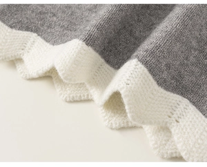 Detailed macro view of the grey knit hem featuring white scalloped edges and cutout patterns