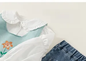 Détails du gilet tricoté avec broderie fleurie et col de chemise à volants fille