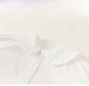 Détail d'une chemise blanche pour tout-petit avec col Peter Pan et bords plissés