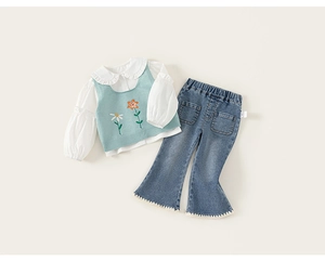Détail du chemisier à col volanté avec pull sans manches à fleurs et jean évasé
