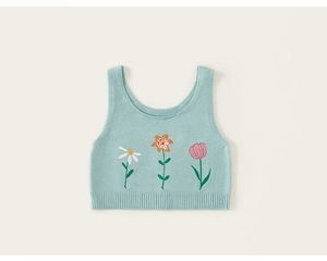 Détail du gilet en tricot vert menthe avec motifs brodés de marguerites et de tulipes