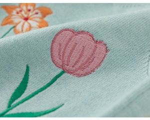Gros plan sur tissu en maille avec broderie florale détaillée de fleurs roses et orange