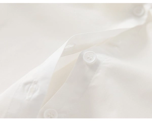 Détail des boutons sur la patte de boutonnage d'une chemise blanche pour fille