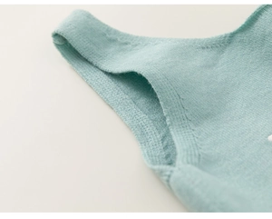 Détail d'un gilet en tricot vert clair montrant les coutures et la poche pour coussinets