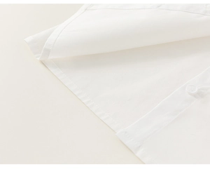 Détail de l'ourlet et des boutons d'une chemise blanche en tissu lisse de haute qualité