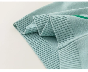 Gros plan sur un tissu en maille vert menthe montrant les coutures et la bordure côtelée