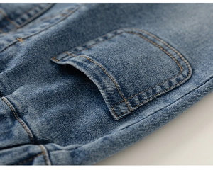 Vue détaillée du tissu denim avec doubles surpiqûres orange et une poche plaquée arrondie