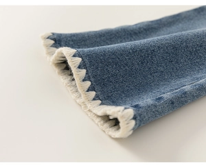 Détail des poignets en denim bleu avec surpiqûres décoratives blanches et texture du tissu