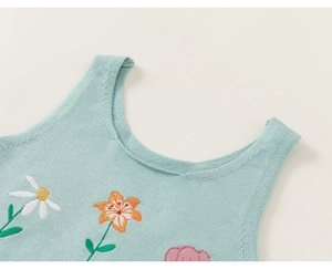 Détail d'un gilet tricoté pour enfants avec broderies florales colorées et texture douce
