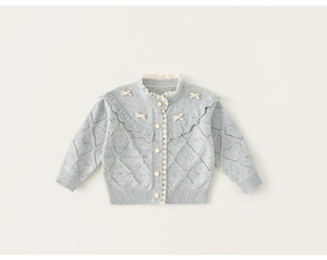 Detail van lichtblauw gebreid vest met kanten rand en kleine crème strikaccenten