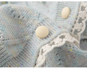 Gedetailleerd macro-opname van lichtblauw gebreid vest met glittervezels en kantrand