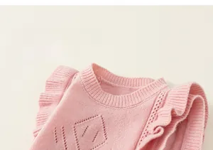 Detail of pink knitted girl vest featuring ruffled sleeves and diamond hollow patterns