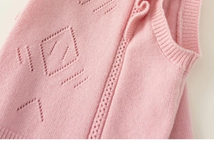 Close-up of pink knitted vest showing delicate hollow diamond pattern and ribbed edges
