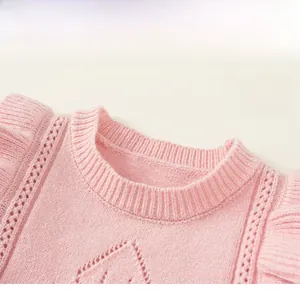 Close-up of pink knit sweater vest with ruffled shoulder trim and hollow pattern