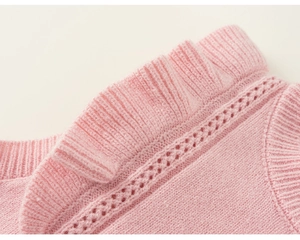 Close-up of pink knit vest featuring ruffled collar and delicate pointelle texture