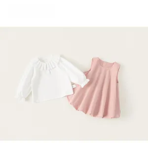Détail à plat d'une chemise en coton à col volanté blanc et robe rose sans manches