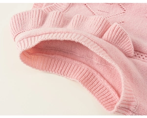 Detail of pink knitted vest showing ruffle edges and delicate hollow diamond textures