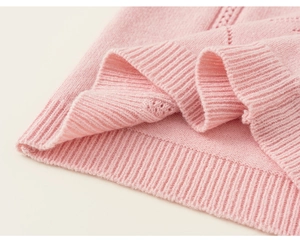 Detail of pink knit vest featuring hollow weave patterns and ribbed hem finish