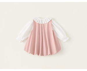 Détail d'un chemisier blanc à manches longues à volants et robe rose sans manches pour fille