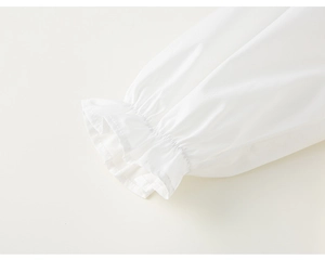 Vue détaillée des poignets élastiques à volants sur une blouse blanche en coton pour fille