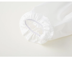 Détail de la manchette blanche à manches longues avec bord à volants et couture soignée