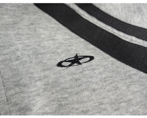Macro detail of high-quality grey knit fabric with embroidered star logo and black ribbed trim