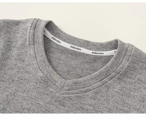 Close-up of the V-neckline detail on the grey knitted sweater with branded neck tape