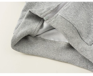 Detailed macro view of the ribbed hem and zipper of a gray boys hoodie sweater