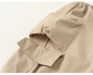 Detail of khaki cargo pants showing functional pocket with adjustable drawstring and flap