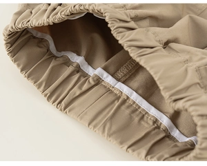 Detail of khaki trousers featuring an elastic waistband and reinforced white piping seams