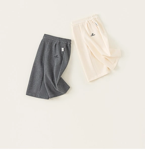 Detailed close-up of grey and beige cotton knit casual trousers for children with logo