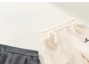 Detail of children's knitted joggers with elastic waist and delicate letter embroidery