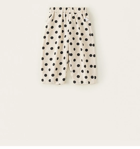 Detail view of elastic waistband and side pockets on beige polka dot toddler pants