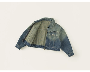Detail of blue cropped denim jacket featuring embroidery on pocket and zipper closure