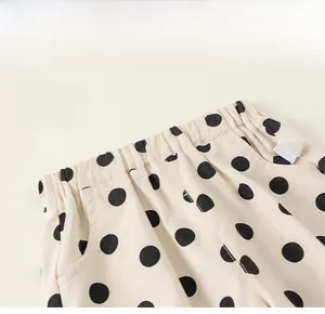 Detail of children's beige polka dot pants featuring an elastic waistband and side pockets