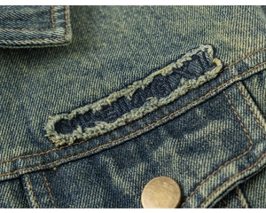 Detailed close-up of vintage washed denim fabric with embroidery and metallic buttons