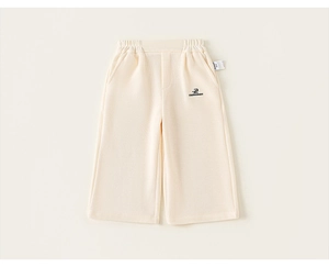 Detail view of cream white kids wide-leg trousers with elastic waist and small embroidery