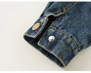 Detailed close-up of dark blue denim sleeve cuffs with vintage metal buttons and contrast stitching