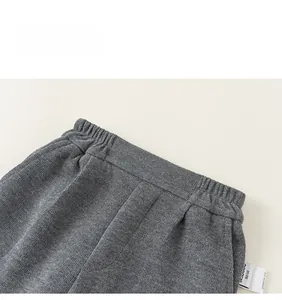 Detail view of children's grey knit trousers featuring an elastic waistband and brand label