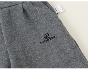 Detail of gray knitted kids trousers with elastic waist and logo embroidery