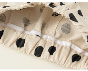 Detailed macro view of children's beige polka dot pants featuring elastic waistband sewing